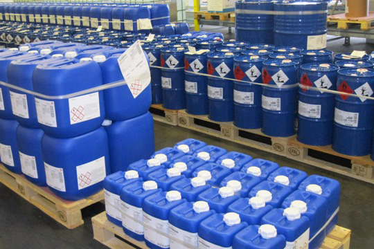 GHS-labels en chemielabels op blauwe kunststof vaten, op pallets.