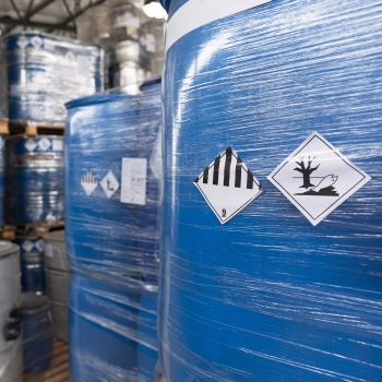 Gevarenstof- en gevaarlijke goederenetiketten: Etiketten voor gevaarlijke goederen op in folie ingepakte containers in de chemische sector.