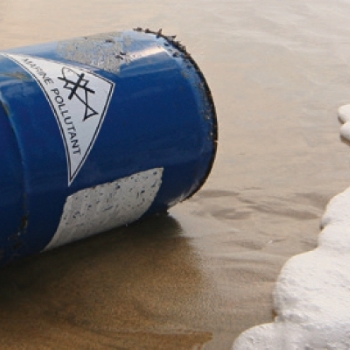 Chemisch vat aangespoeld op de oever, met een zeewaterbestendig etiket.
