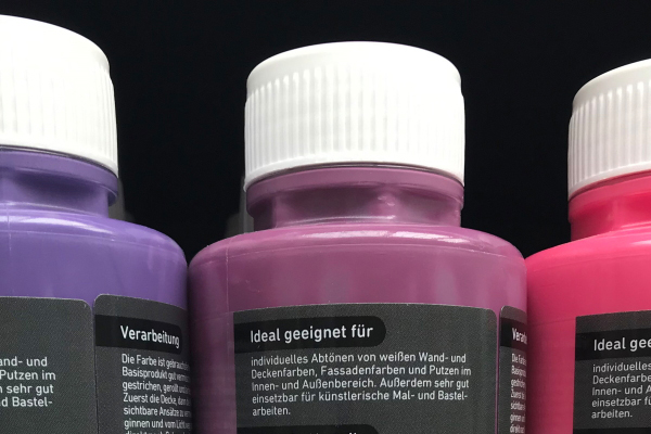 Translation: "Oplossingen voor de bouwmaterialensector: Digitale druklabels op kleurflessen in het bouwmarktrek, detail achterkant.