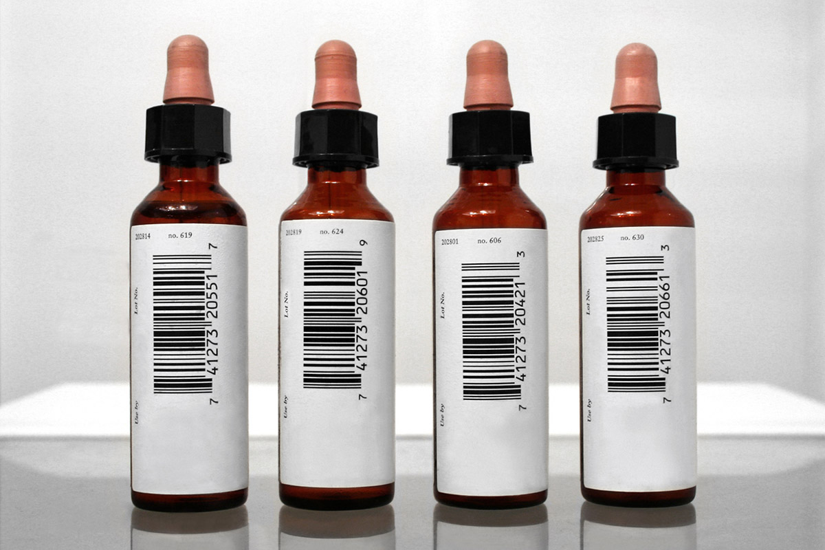 Rondomstickers: Barcode etiketten op vier bruine medicijnflesjes met pipetdop