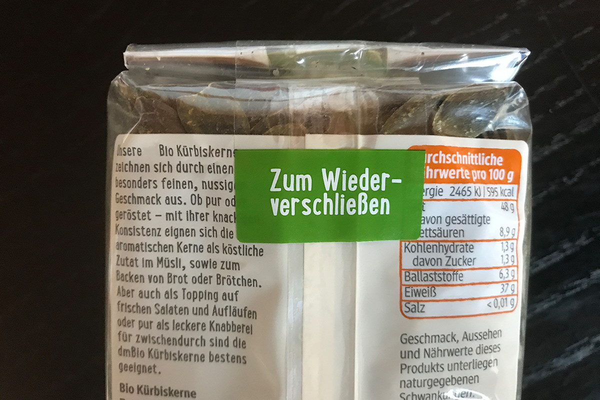 Verzegeling etiketten: transparant herbruikbaar etiket met gekleurde handgreep, op zakverpakking met pompoenpitten.