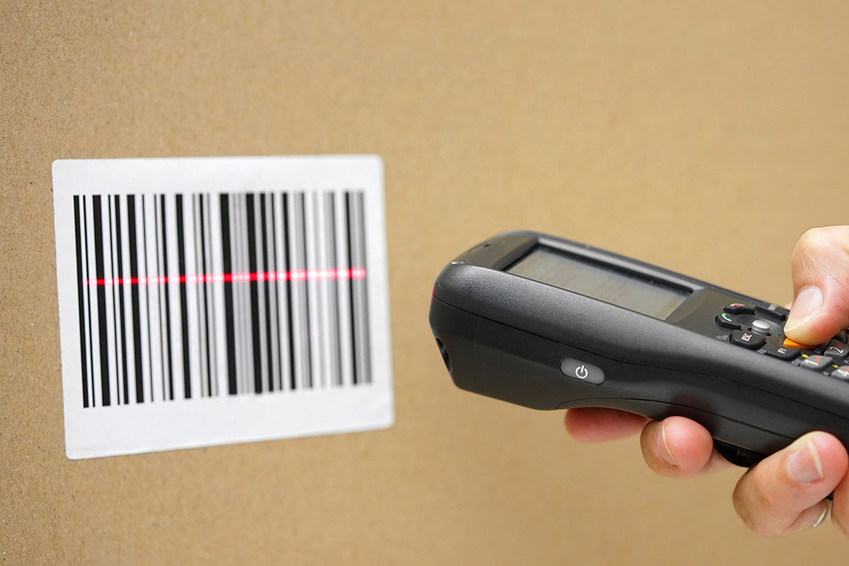 Barcode-labels: Barcode-label op bruin karton met handscanner en rode scannerlijn