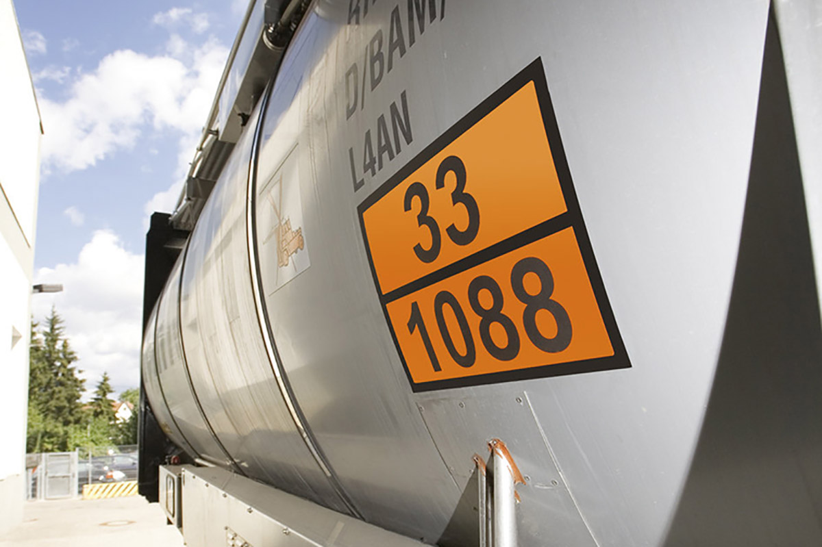 Gevarenstoffen- en gevaarlijke goederenetiketten: Oranje waarschuwingsbord met identificatienummers op een zilveren tankwagen.