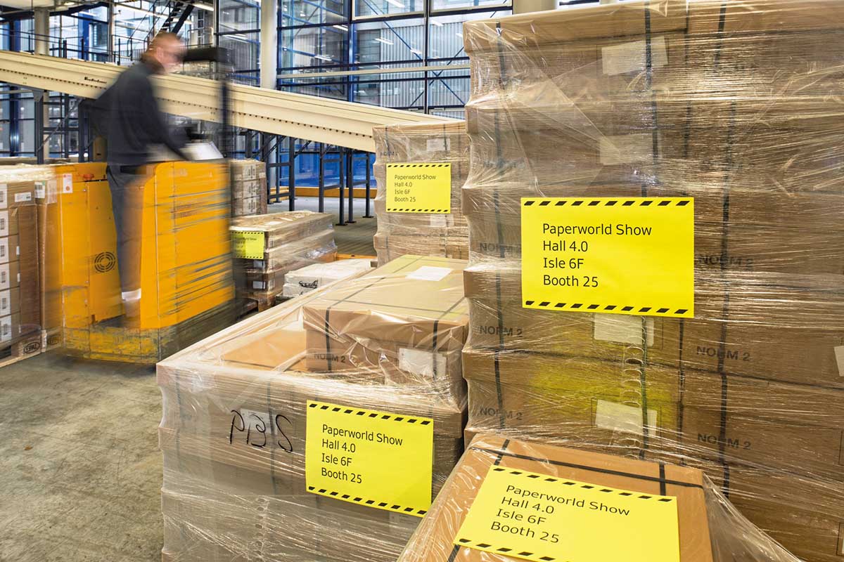 Verzend- en palletlabels: Gele folie labels op ingekrompen pallets in het magazijn, met een heftruck.