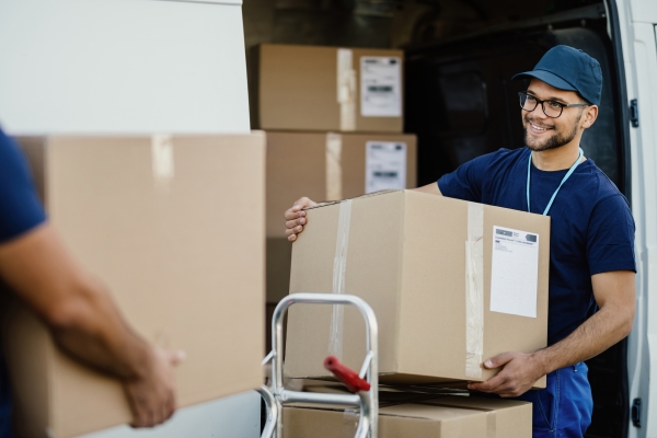 Verzend- en palletlabels: Pakketbezorging met een bestelwagen, de expeditiemedewerker plaatst de verzenddoos op een palletwagen.