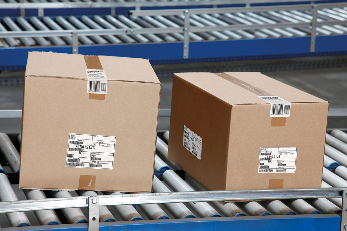 Verzend- en palletlabels: verzendlabel op bruine dozen, op de transportband in de logistiek, aan de zijkant.