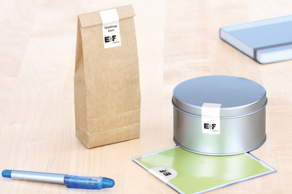 Sluitstickers: Witte sluitstickers op een bruine tas, een metalen blik en een plastic zak.