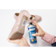 Eine Hand hält einen beigen High Heel mit einem Etikett, während die andere Hand eine Spraydose mit Etikettenentferner hält.