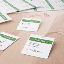 Modeetiketten in verschiedenen Größen und Farben, darunter grau, blau und grün, auf einem Holzuntergrund angeordnet.