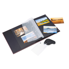 Ein offenes Fotoalbum mit mehreren Bildern, darunter Landschaften, und einem Schlüsselanhänger auf der Seite.