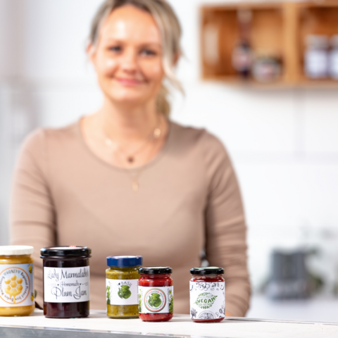 Fünf Glasbehälter mit verschiedenen Lebensmitteln: Mehl, Reis, Müsli, Pasta und Haferflocken, jeweils mit beschrifteten Etiketten.