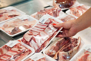 Voedseletikettering: productetiket, voedseletiket op vleesverpakking, vrouw haalt goederen uit de koeltoonbank.