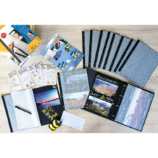 Ein Scrapbook-Set mit leeren Seiten, Aufklebern, einem Stift und einer Auswahl an Fotos, die in einem Album angeordnet sind.