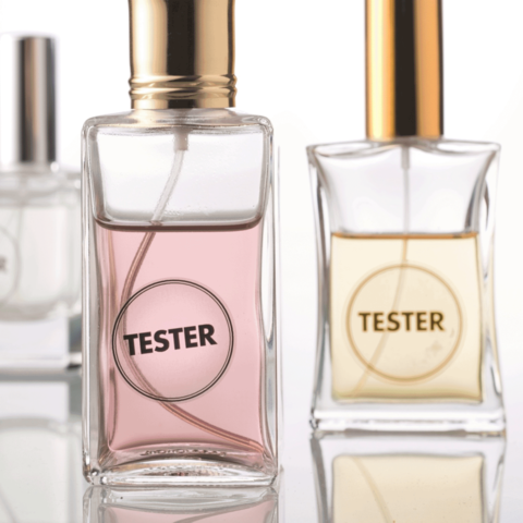 Drei Parfümflaschen mit dem Aufdruck "TESTER", eine mit rosa Flüssigkeit und zwei mit klarer Flüssigkeit, stehen nebeneinander.