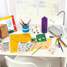 Fel gekleurde bureau met knutselmaterialen, stickers, pennen, een map en een lamp.