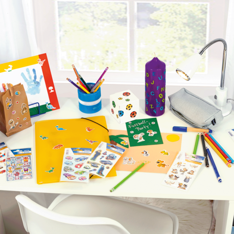 Fel gekleurde bureau met knutselmaterialen, stickers, pennen, een map en een lamp.