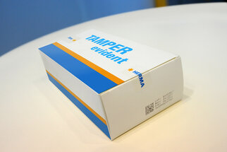 Verpakking met de opdruk "TAMPER evident" in blauw en oranje, geproduceerd door HERMA.