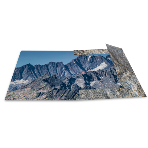 Berglandschaft mit schroffen Gipfeln und Gletschern, die sich über eine weite Fläche erstrecken. Klare Himmel und felsige Strukturen sind sichtbar.