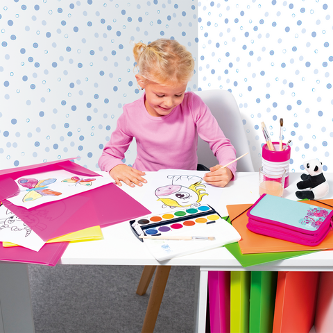Een klein meisje zit aan een tafel, schildert met waterverf en is omringd door kleurrijk papier en tekeningen.