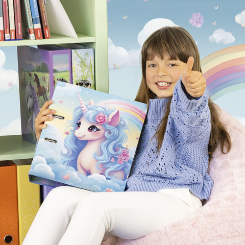 Ein Mädchen mit braunen Haaren sitzt auf einem Sessel und zeigt Daumen hoch, während sie einen Ordner mit einem Einhorn-Design hält.