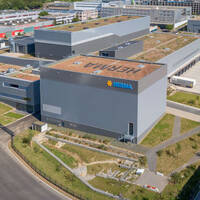 Moderne industriële gebouwen met groene daken en het logo van Merima, omringd door straten en groenvoorzieningen.