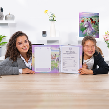 Twee meisjes zitten aan een tafel en houden een open schrift vast met een certificaat en een leeg vel papier. Op de achtergrond zijn decoratieve elementen zichtbaar.