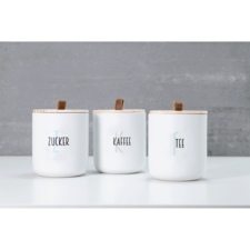 Drei weiße Behälter mit Holzdeckeln, beschriftet mit "Zucker", "Kaffee" und "Tee".
