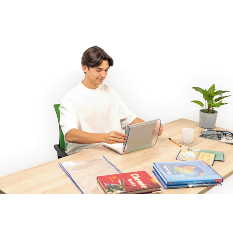 Ein junger Mann sitzt an einem Tisch und arbeitet mit einem Laptop. Auf dem Tisch liegen mehrere Bücher und eine Pflanze.