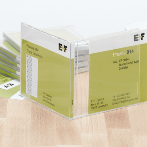 Ein Ordner mit dem Titel "Photos 014" für Handelsmessen in Asien, mit Kontaktdaten und Jobnummer.