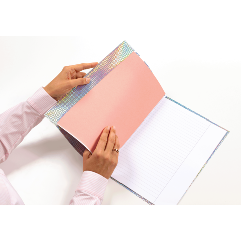 Eine Person hält ein Notizbuch mit einem bunten Einband und einer leeren, linierten Seite im Inneren.