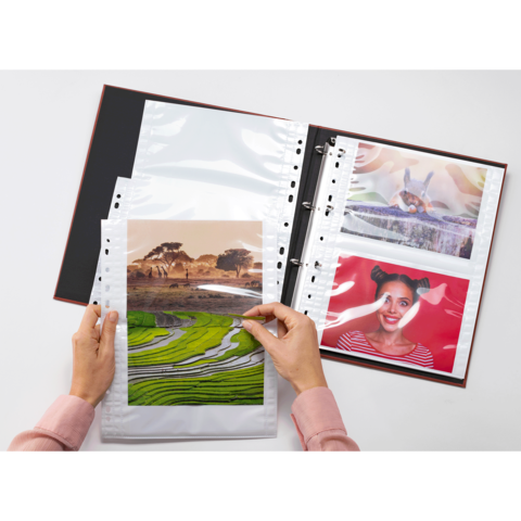 Eine Person hält ein Foto von einer Landschaft mit Reisfeldern, während ein Fotoalbum mit weiteren Bildern geöffnet ist.