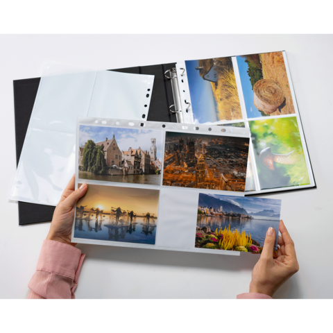 Eine Person hält ein Fotoalbum mit mehreren Bildern von Landschaften, Gebäuden und Naturmotiven in der Hand.