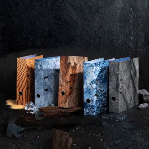 Farbenfrohe Ordner in verschiedenen Texturen und Mustern stehen auf einer dunklen Oberfläche.