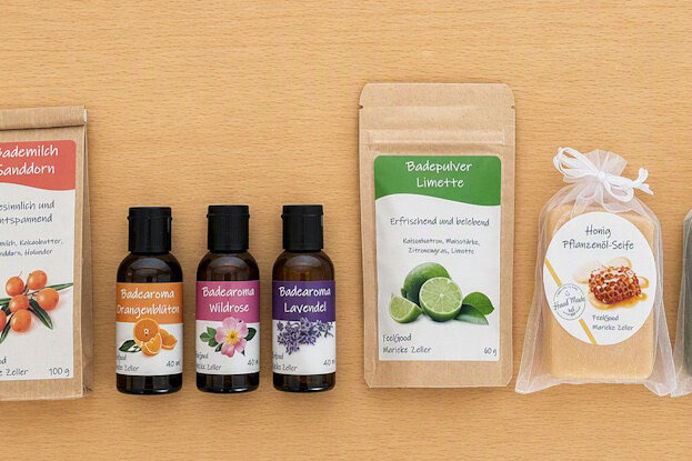Individuele etiketten voor cosmetische producten in een serie: plantaardige zeep in doorzichtige zakken, Doypacks met badmelk en badpoeder, en bruine glazen flessen met badaroma, op een lichte houten ondergrond.