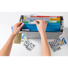 Hände sortieren farbige Akten in einem Ordner mit beschrifteten Trennblättern. Daneben liegen Etiketten und Aufkleber.