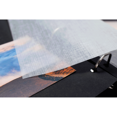 Transparente Folie liegt über Fotos in einem Ordner, der schwarze Seiten hat. Die Fotos zeigen Landschaften mit Himmel und Bergen.