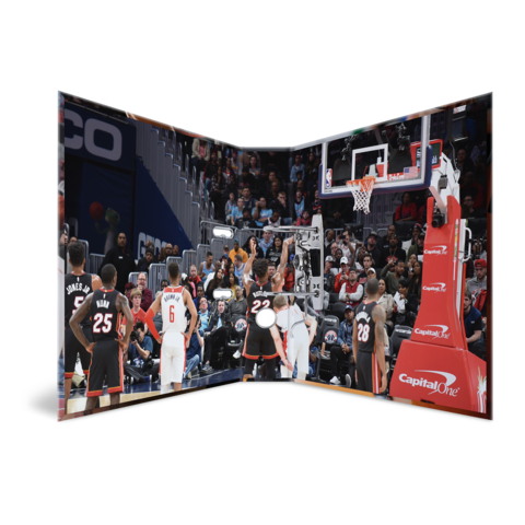 Basketballspiel mit Spielern in Aktion, Zuschauer im Hintergrund, Korb und Spielfeld sichtbar.