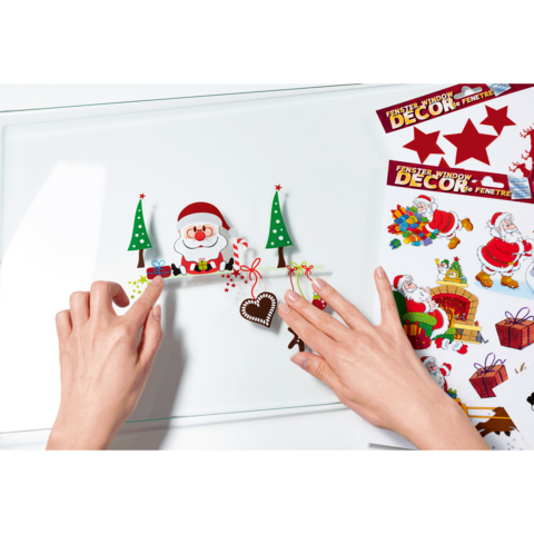 Hände platzieren Weihnachtsdekorationen, darunter ein Weihnachtsmann, Weihnachtsbäume und ein Herz, auf einer glatten Oberfläche.