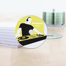 CD met de titel 'Greatest Hits', afgebeeld met een DJ-ontwerp op een gele achtergrond, naast een stapel CD-hoesjes.