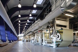 Moderne productiehal met grote machines voor de verwerking van materialen, veel licht en hoge plafonds.