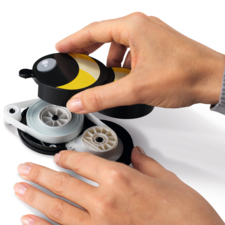 Een hand houdt een gele en zwarte dispenser vast, terwijl een andere hand de draad eruit trekt.