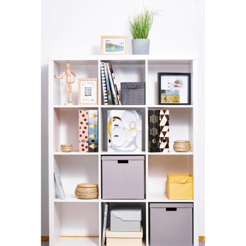 Regal mit mehreren Fächern, gefüllt mit Kisten, Büchern und Dekorationsobjekten, darunter Bilderrahmen und eine Pflanze.